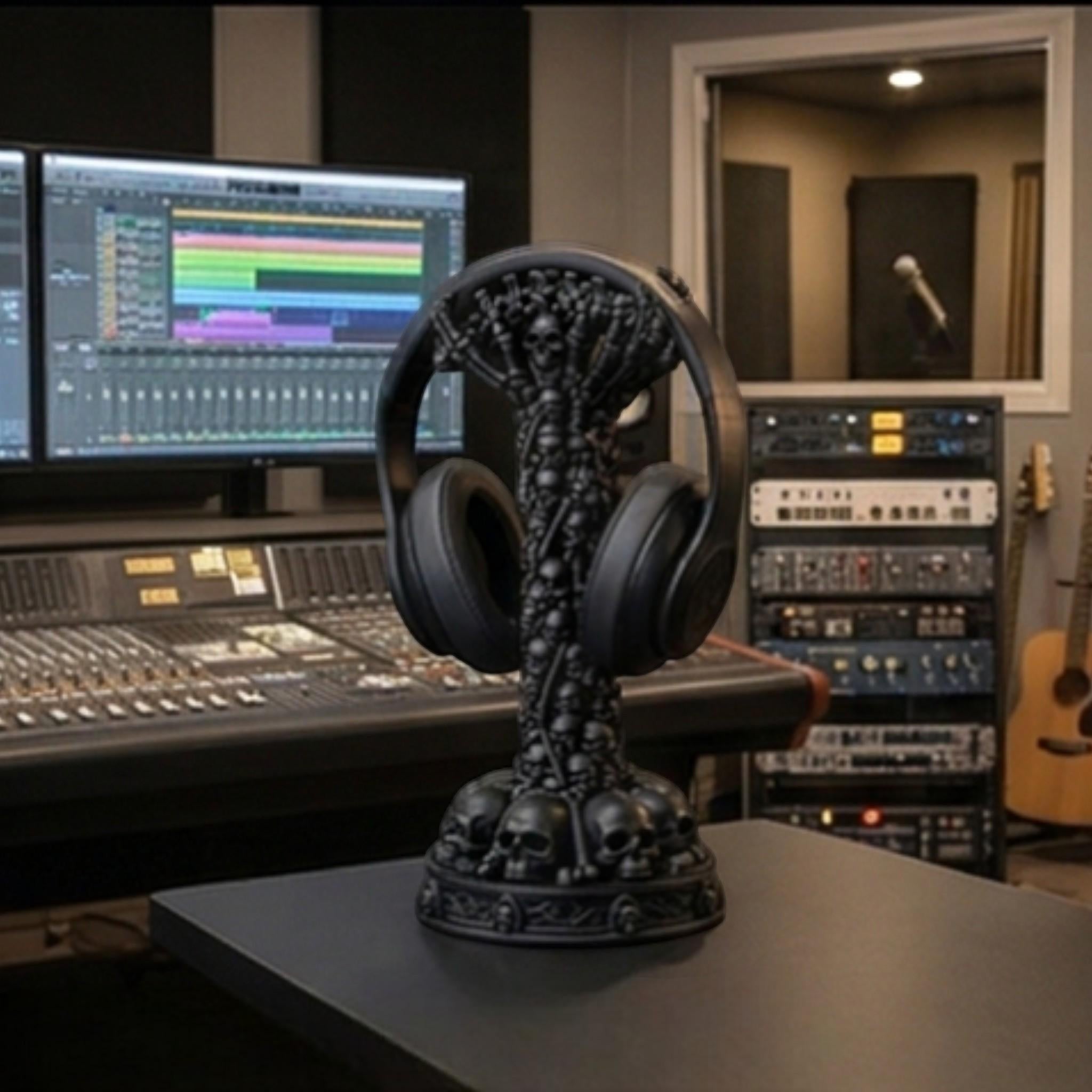 Happy3dWorld matte black skull column headphone stand displayed on a desk in a professional music recording studio.